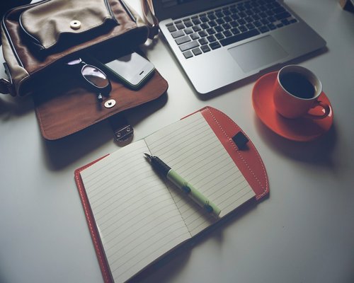 Organized workspace with a warm cup of coffee and a notebook